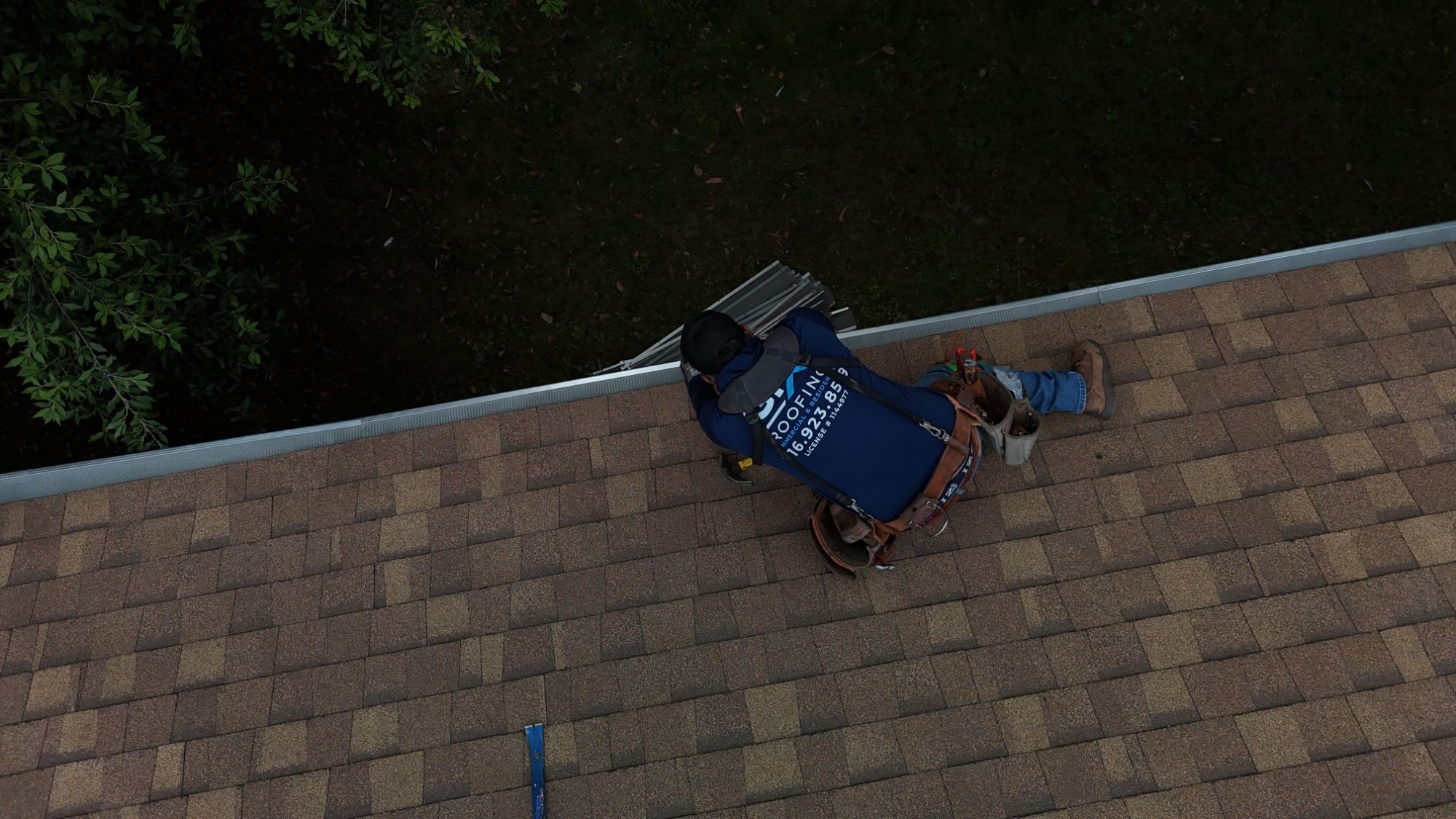 Overhead view of a GM Roofing roofer working at the edge of a shingle roof