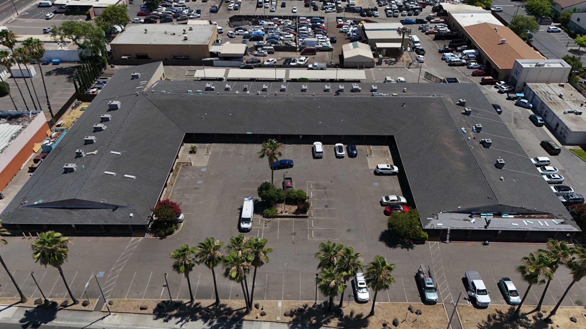 Aerial view of a U-shaped commercial strip mall in Arden during a GM Roofing roof replacement