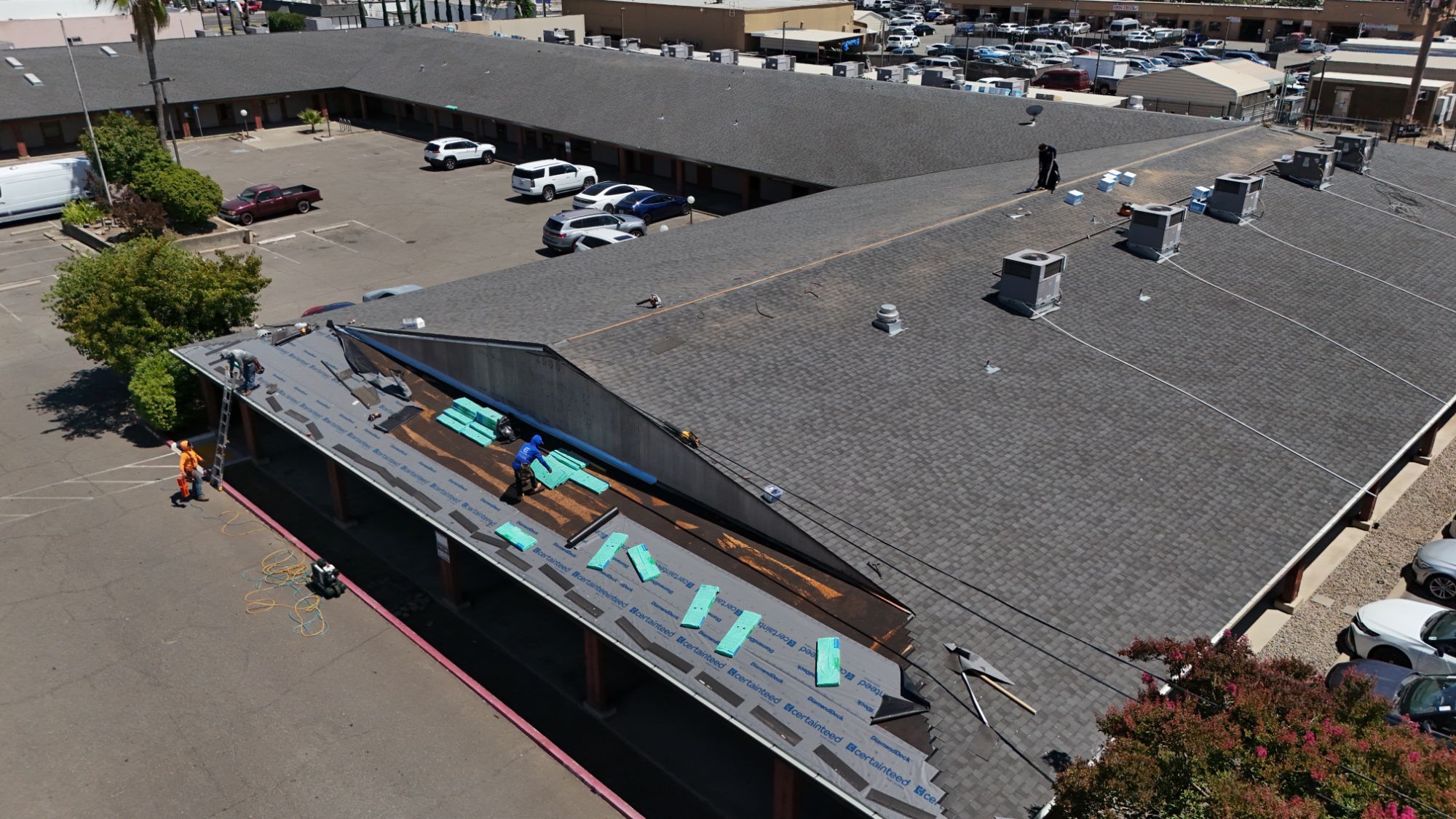 One wing of the Arden strip mall stripped and covered in new underlayment next to the finished shingle roof