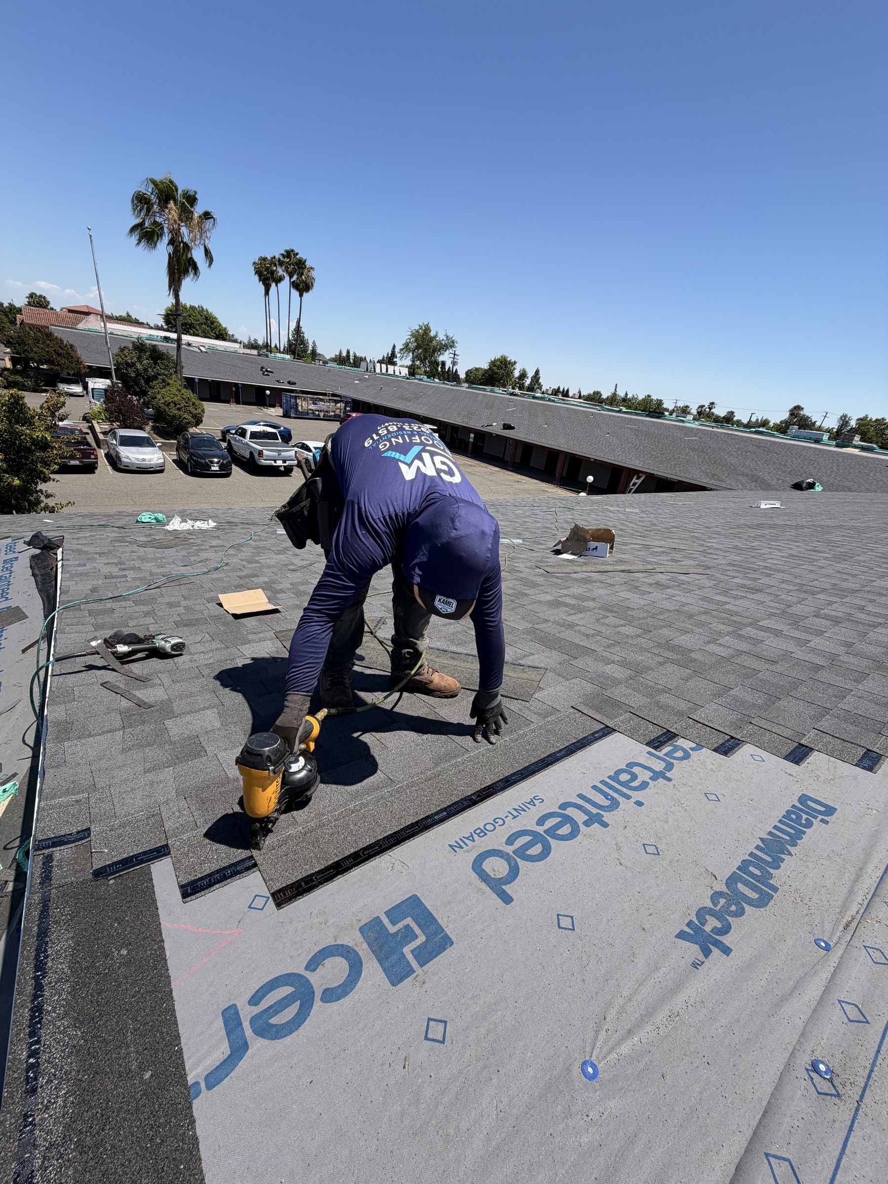 GM Roofing roofer nailing new shingles over CertainTeed underlayment on a Sacramento commercial building