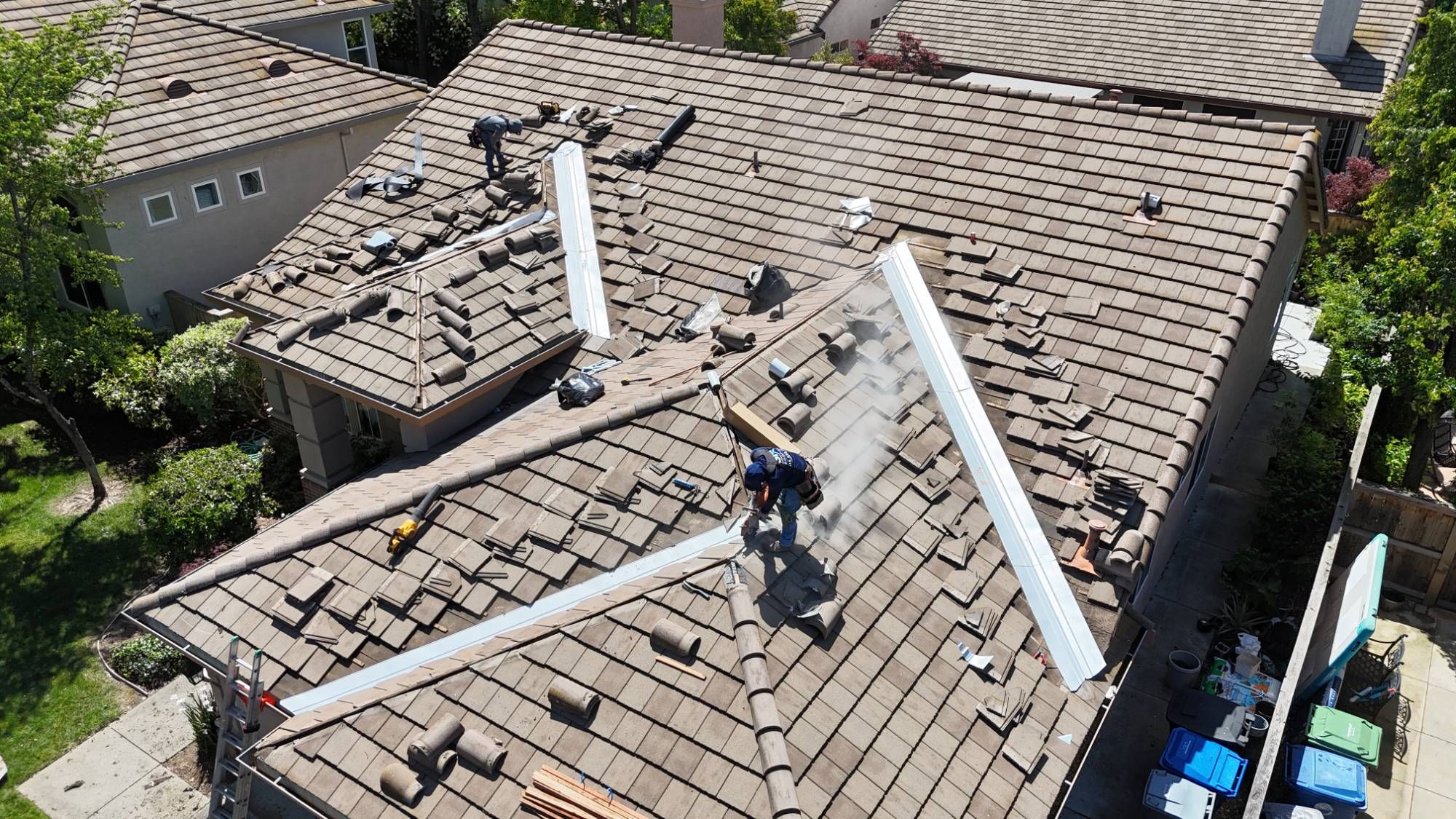 GM Roofing crew cutting concrete tile beside new metal valley flashing on a Sacramento home