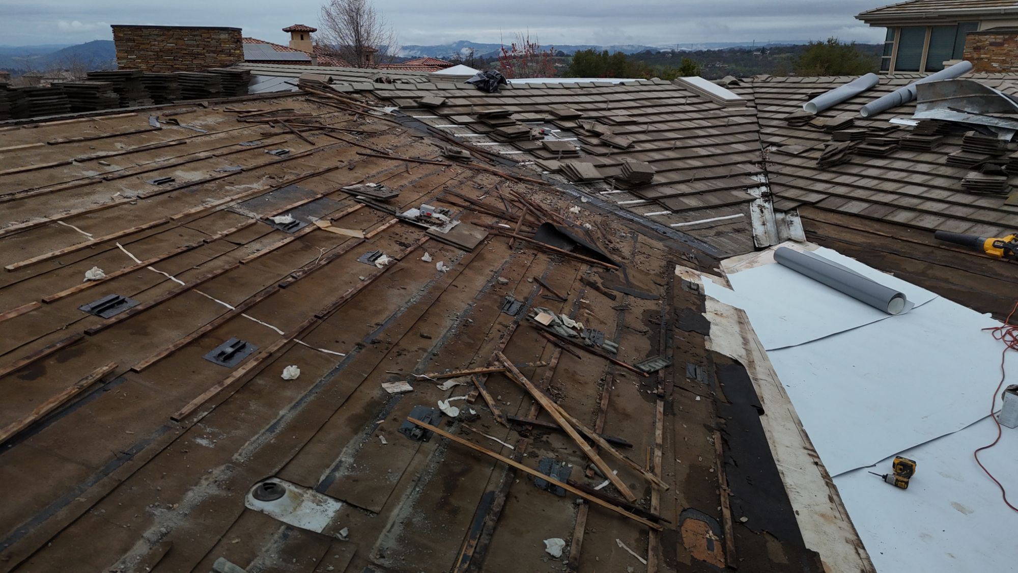 Tile lifted off a Sacramento roof showing the worn old underlayment and battens underneath